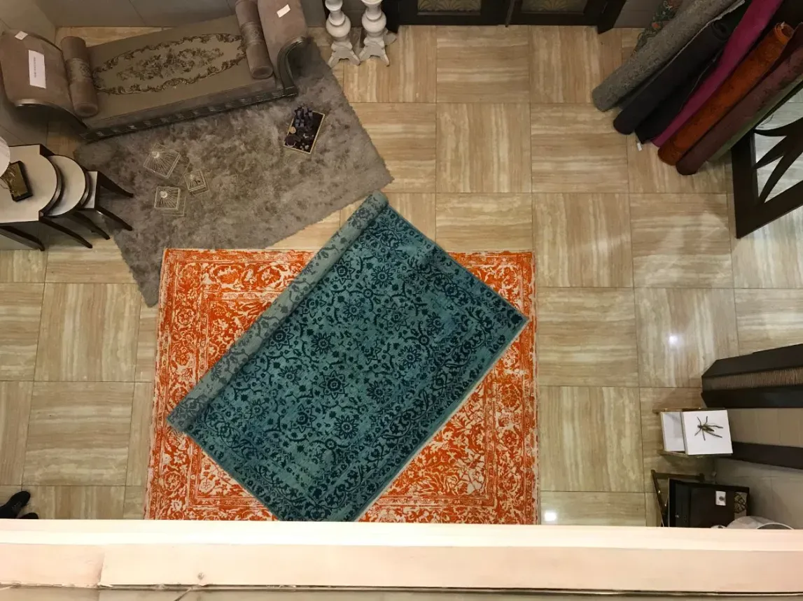 A teal and an orange area rug laid out on the tiled floor of the Simply Clean Care rug facility