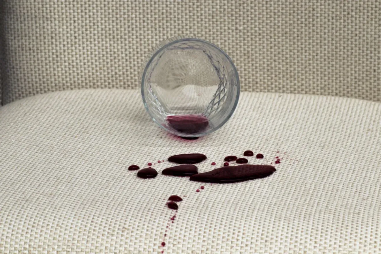 A red wine spill on a cream upholstered cushion before treatment